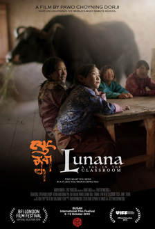 [poster with white Lunana text alongside red calligraphy, in front of small, rural children sitting at a table with a black yak in background]