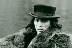 Johnny Depp, wearing a bear skin coat and John Bull Topper hat, stares out with a glazed look]