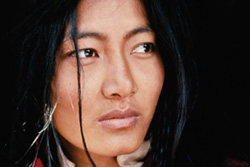 [close up of asian woman with long black hair stares pensively to her left]