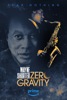 [blueish-grey poster of black man’s head looking forward, blended at the top right to a golden lit profile of his head and hands playing a saxophone, with fear nothing in blue capital letters at top, and wayne shorter in stacked white capital letters, tucked into stacked golden capital letters zero gravity where the o is a phase of the sun, and with prime in lower case blue letters over a curved arrowed shaped like a smile]